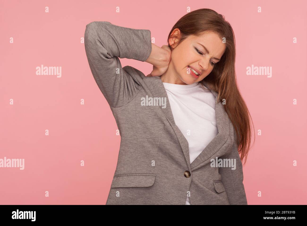Ritratto di una giovane donna stressata in overworked in tuta da lavoro che tocca il collo doloroso, che soffre di dolori muscolari, che fa male alle spalle, che si sente malsana Foto Stock