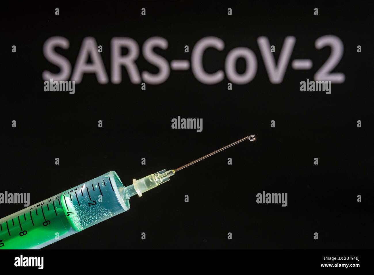 Questa figura mostra una siringa monouso con ago ipodermico, SARS-COV-19, scritta su una scheda nera dietro Foto Stock