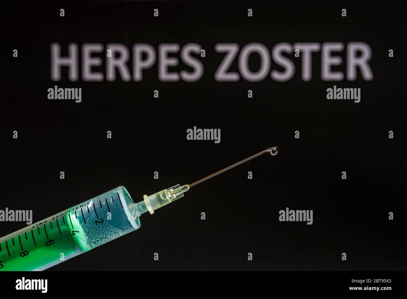 Questa illustrazione della foto mostra una siringa monouso con ago ipodermico, HERPES ZOSTER scritto su una lavagna nera dietro Foto Stock