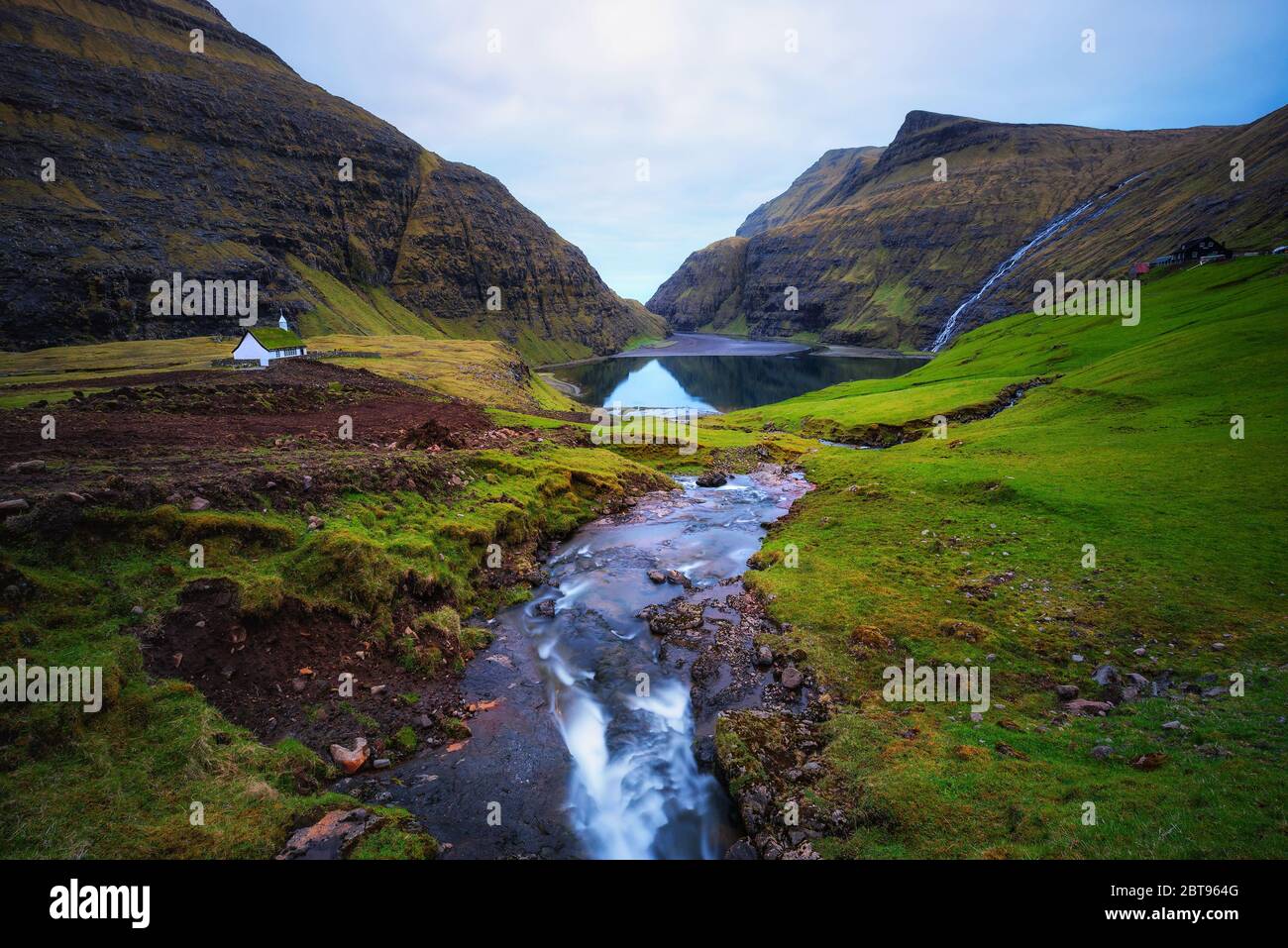 Lago e una piccola chiesa bianca a Saksun sulle isole Faroe, Danimarca. Foto Stock