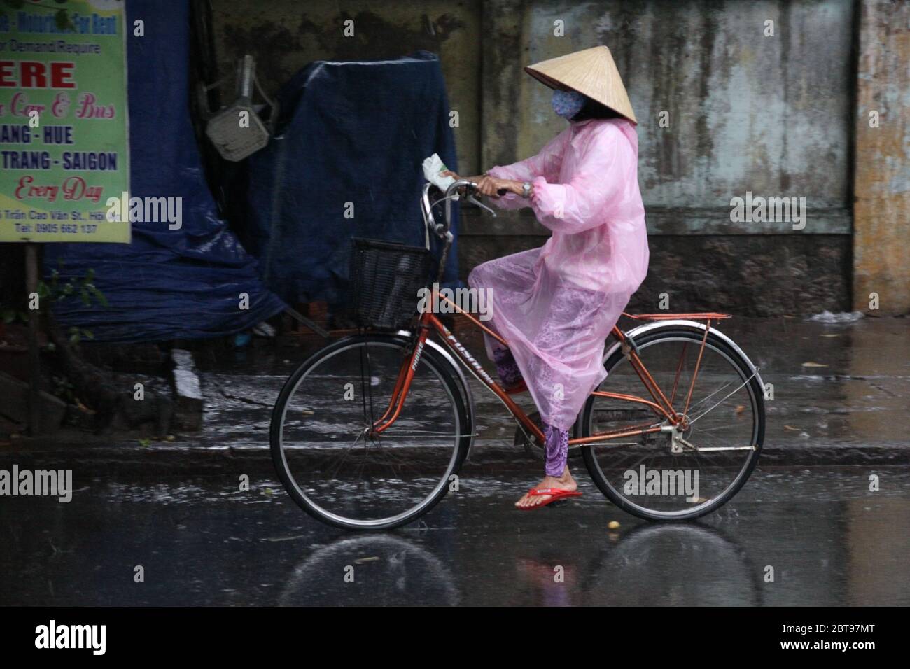 Ciclista del Vietnam sotto la pioggia Foto Stock