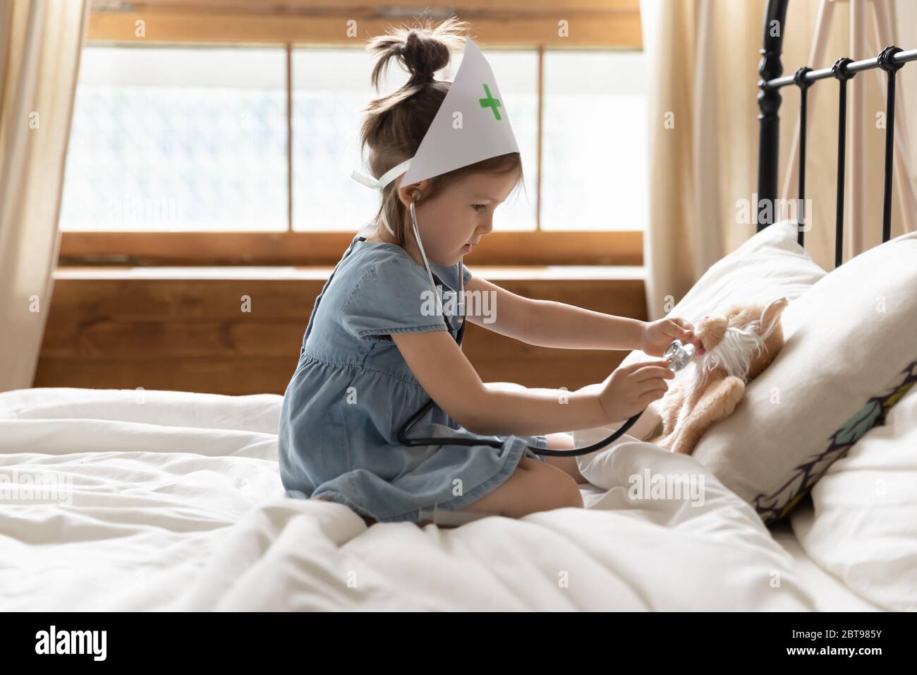 Carina bambina vestita come medico giocando con giocattolo Foto Stock