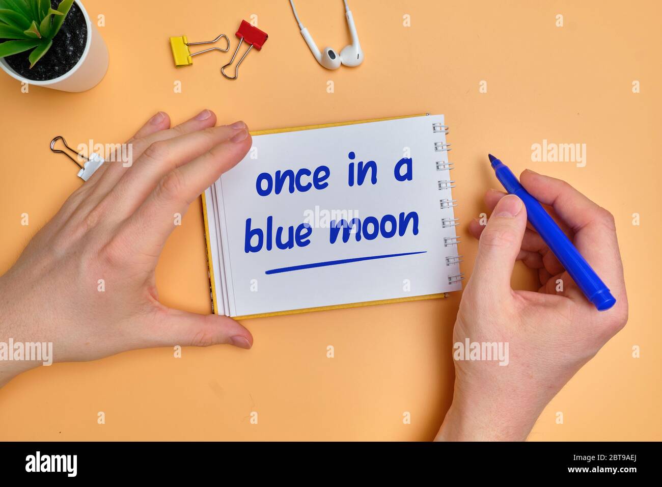 Idioma inglese lancetta a mano circa il tempo - una volta in una luna blu su blocchi di legno. Primo piano. Foto Stock