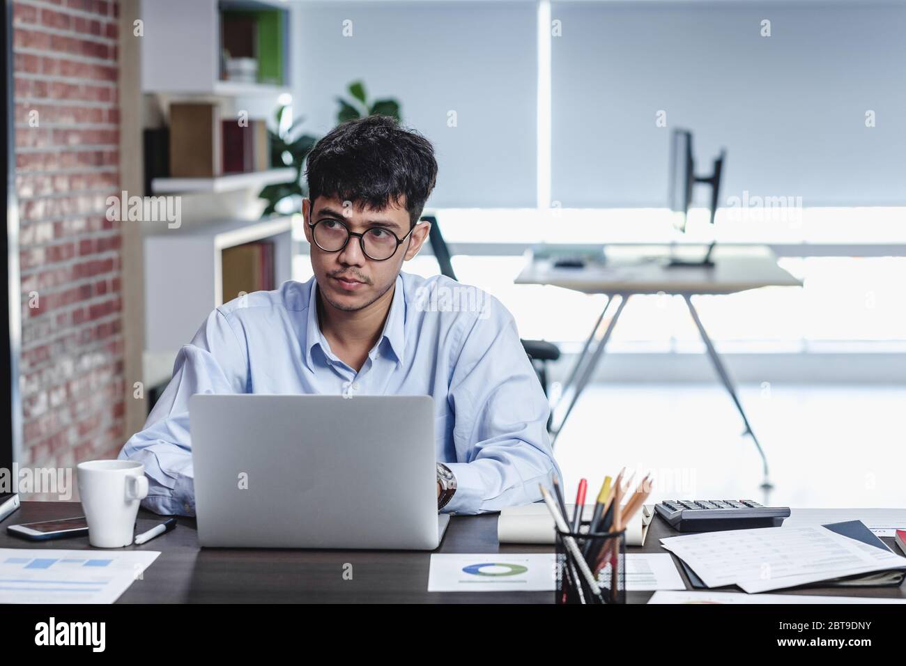 Imprenditore asiatico di Woking con il computer portatile e il foglio di lavoro sulla scrivania in ufficio.workflow digitale business online il concetto di stile di vita Foto Stock