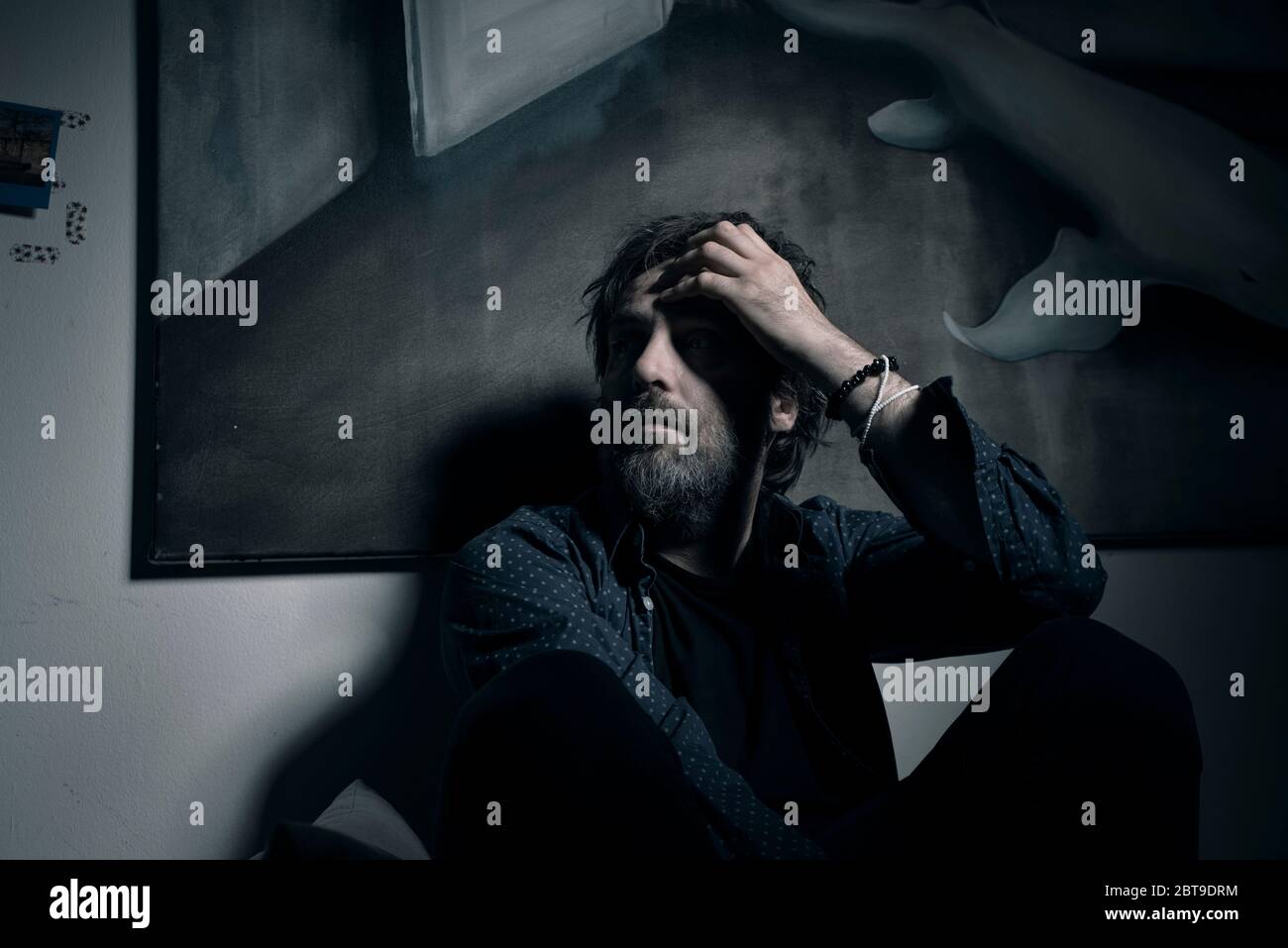 Moody ritratto di un musicista alternativo ceco David Pomahac sotto un dipinto di una balena Foto Stock