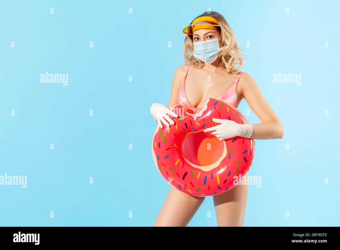 Donna in costume da bagno con anello in gomma, indossando maschera igienica per il viso e guanti chirurgici per prevenire il contagio coronavirus sulla spiaggia del resort, riposo e summ Foto Stock