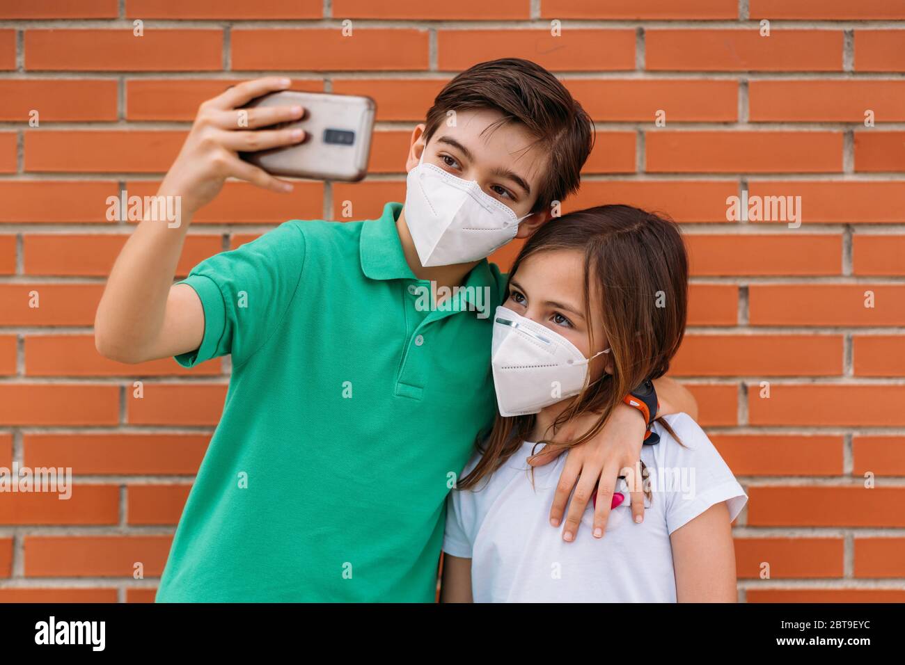 Felice bambino e ragazza che indossa la maschera e prende un selfie con lo smartphone Foto Stock