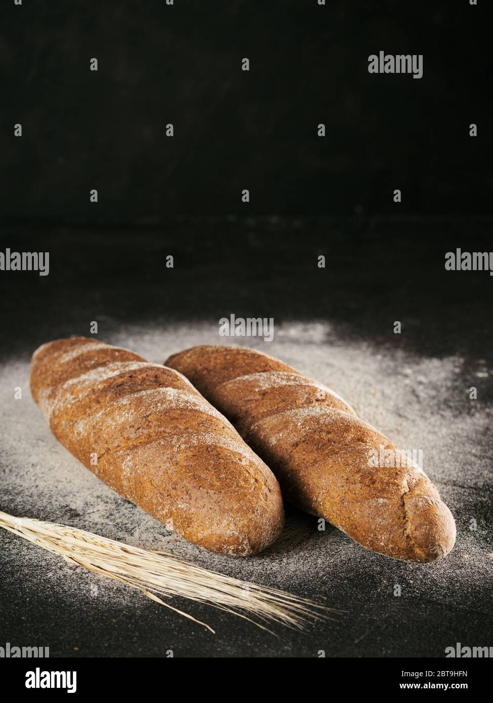 Due interi in casa pane di segale pane di farina di grano saraceno su nero testurizzato sfondo. Copia dello spazio. Tasto basso Foto Stock