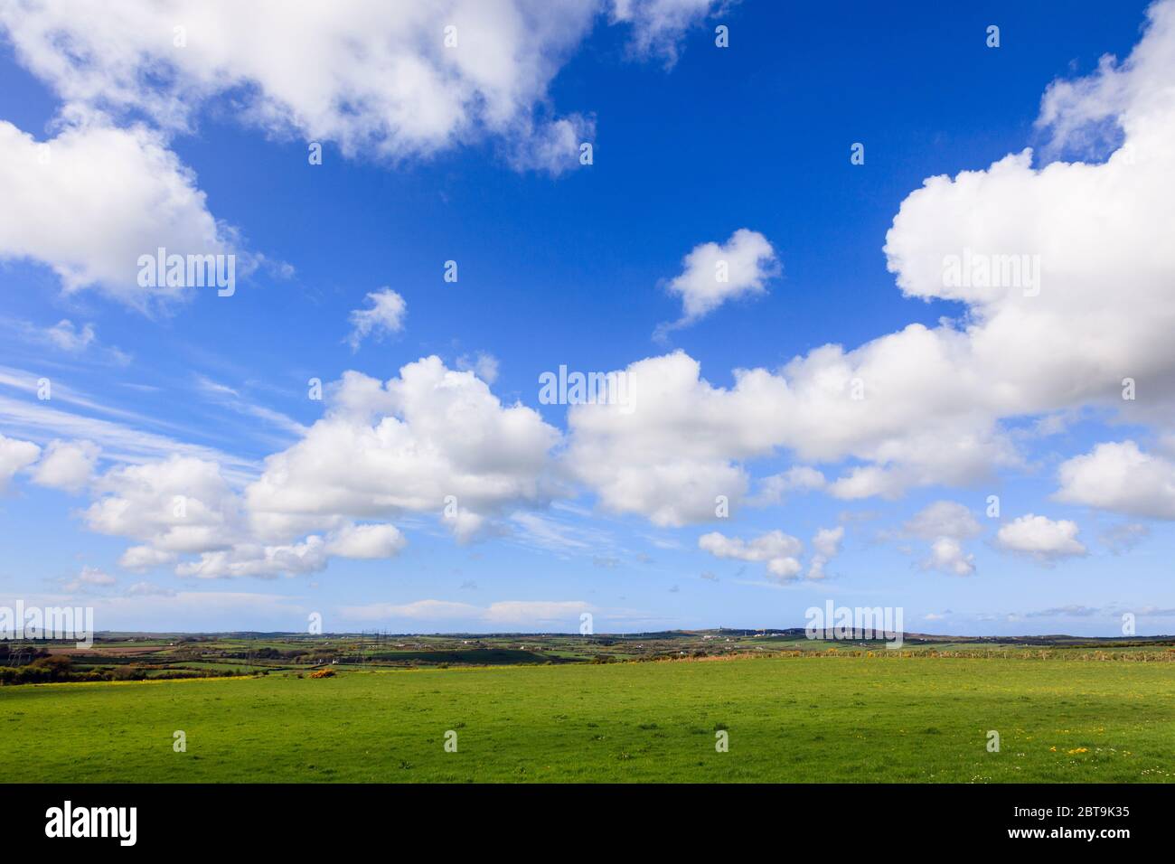 Cielo blu con nuvole bianche che si sussulano attraverso la verde campagna in un paesaggio rurale. Isola di Anglesey, Galles del nord, Regno Unito, Gran Bretagna Foto Stock