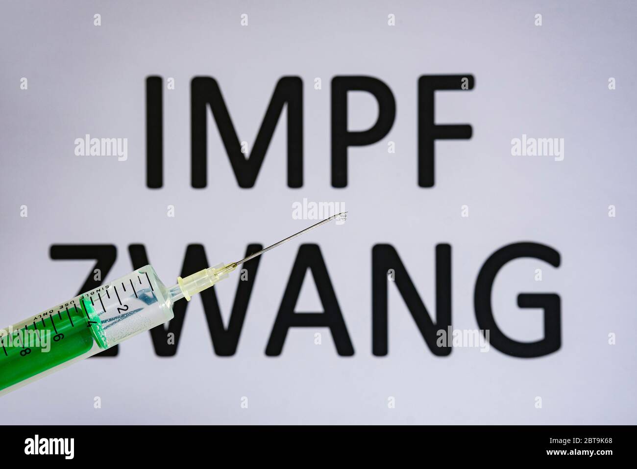 Questa figura mostra una siringa monouso con ago ipodermico, IMPFZWANG scritta su una lavagna bianca dietro Foto Stock