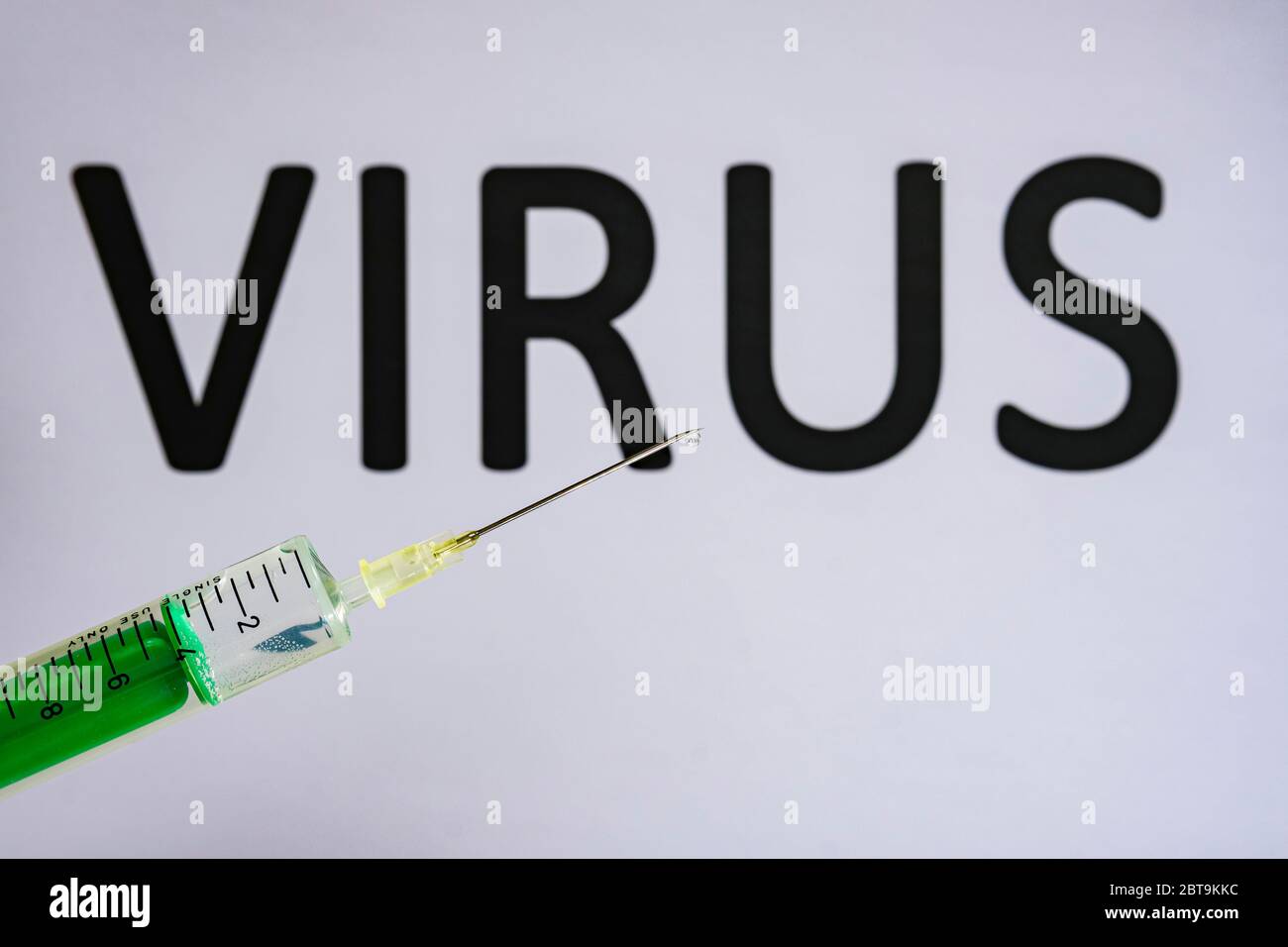 Questa figura mostra una siringa monouso con ago ipodermico, VIRUS scritto su una lavagna bianca dietro Foto Stock