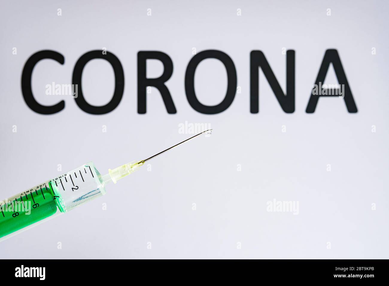 Questa figura mostra una siringa monouso con ago ipodermico, CORONA scritta su una lavagna bianca dietro Foto Stock