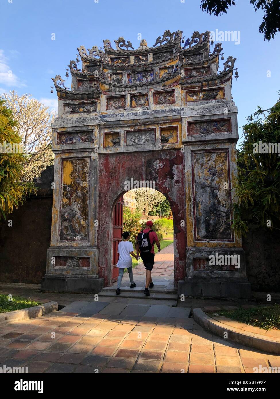 Hue, Vietnam, la città imperiale, i turisti che camminano attraverso un vecchio arco Foto Stock