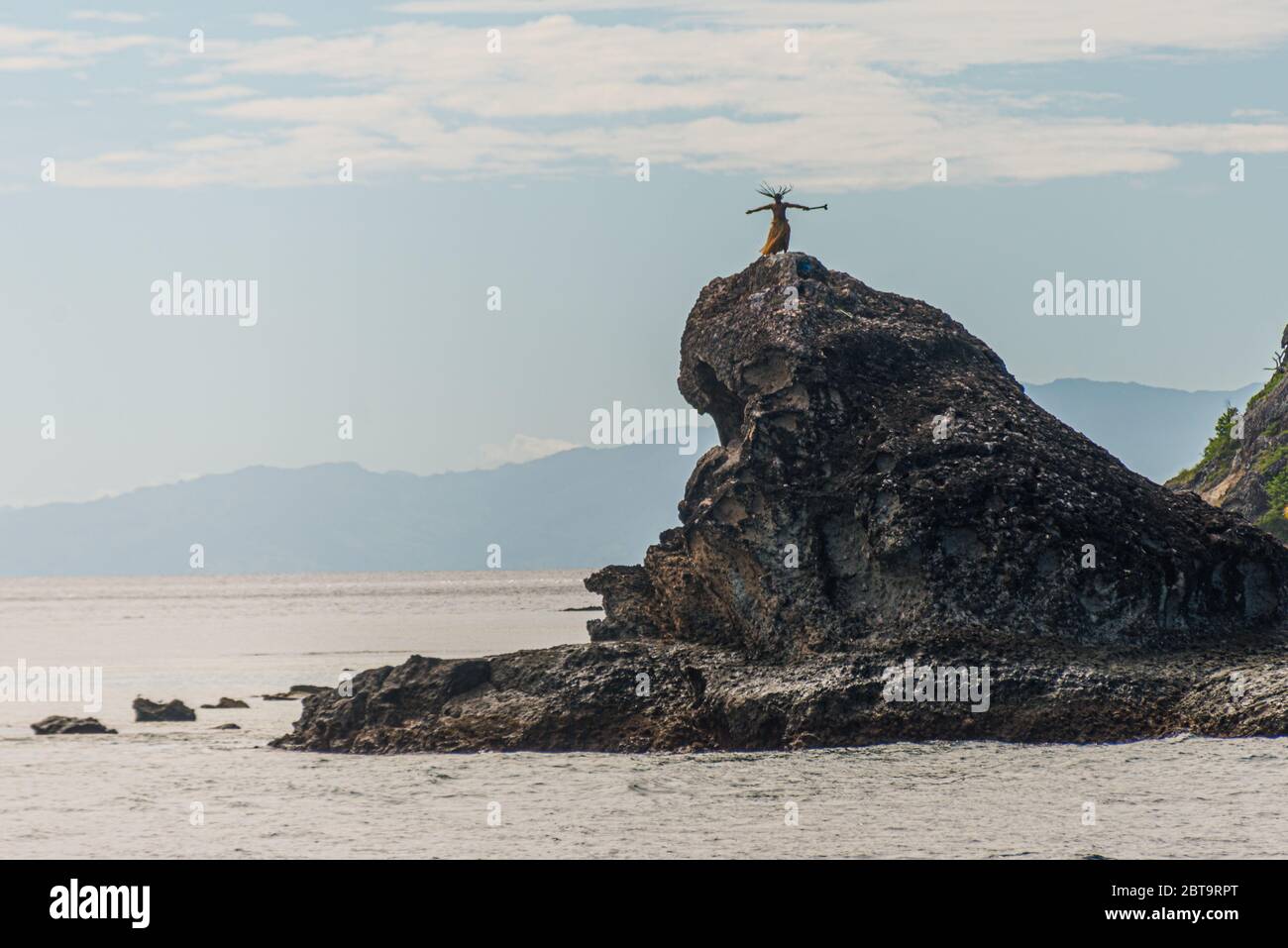 Abitanti dell'isola delle Fiji che ballano su una roccia nel mare, vicino ad un'isola tropicale. Isole Yasawa, Figi Foto Stock