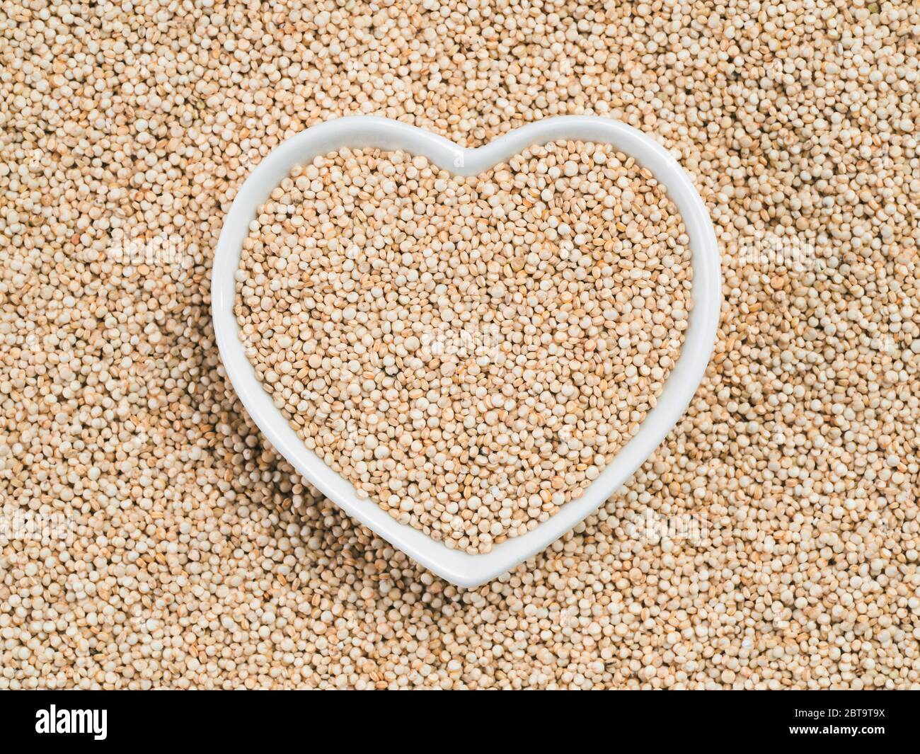 La quinoa in a forma di cuore sulla tazza di quinoa sfondo. Senza glutine di grano antico per una sana dieta. Io amo la quinoa concetto. Copia dello spazio. Foto Stock