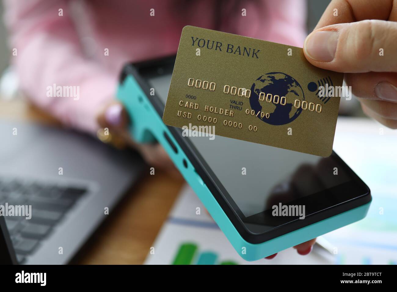 Le dita maschili tengono la carta di credito sopra il terminale Foto Stock