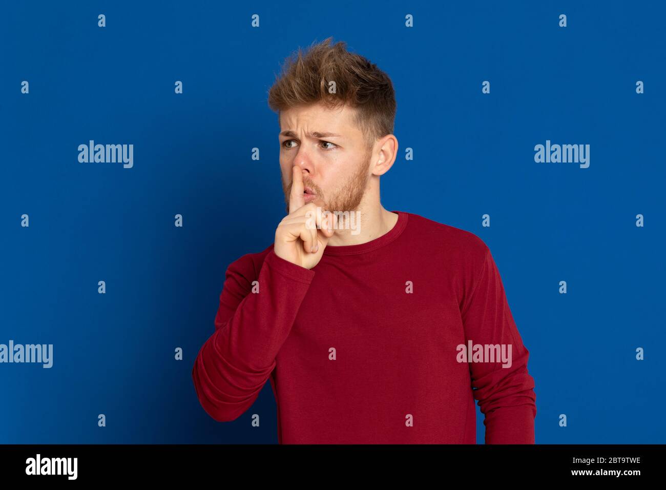 Giovane ragazzo attraente con una T-shirt rossa su sfondo blu Foto Stock