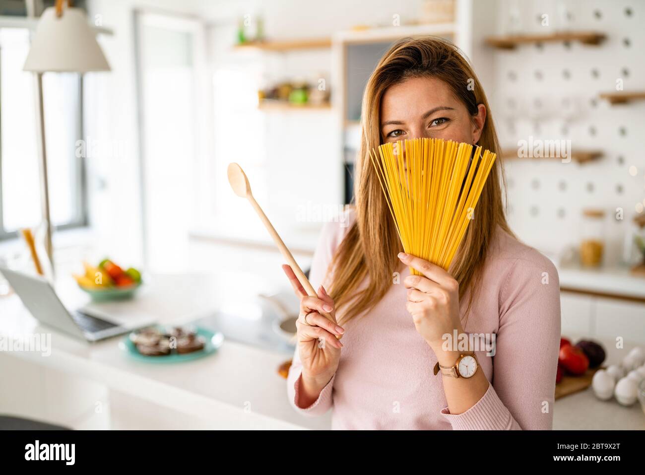 Felice gioiosa donna che tiene lunghi maccheroni di pasta pronti a cucinare. Concetto di cibo sano. Foto Stock
