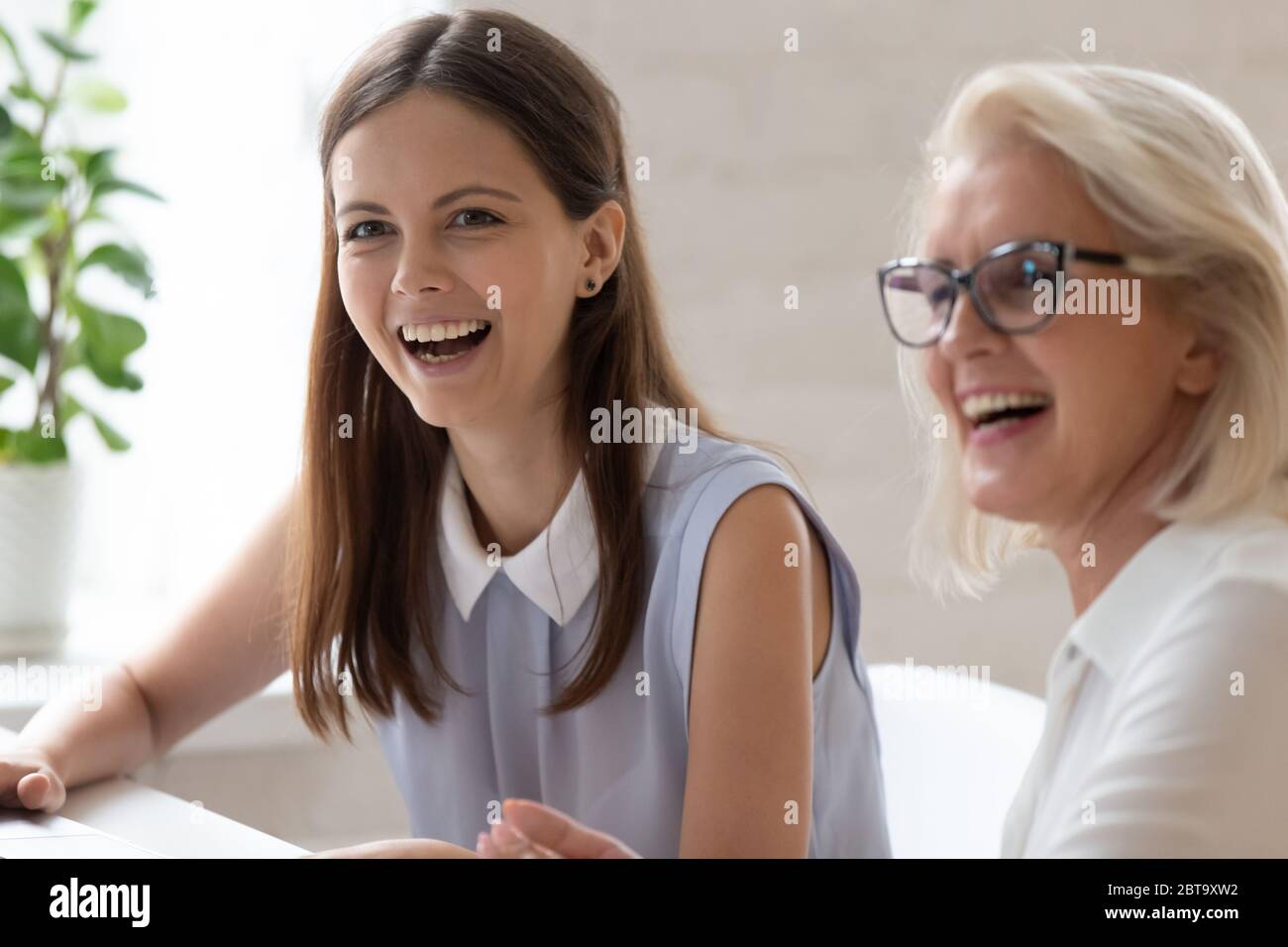 I dipendenti donne felici e diversi ridono a parlare sul posto di lavoro Foto Stock
