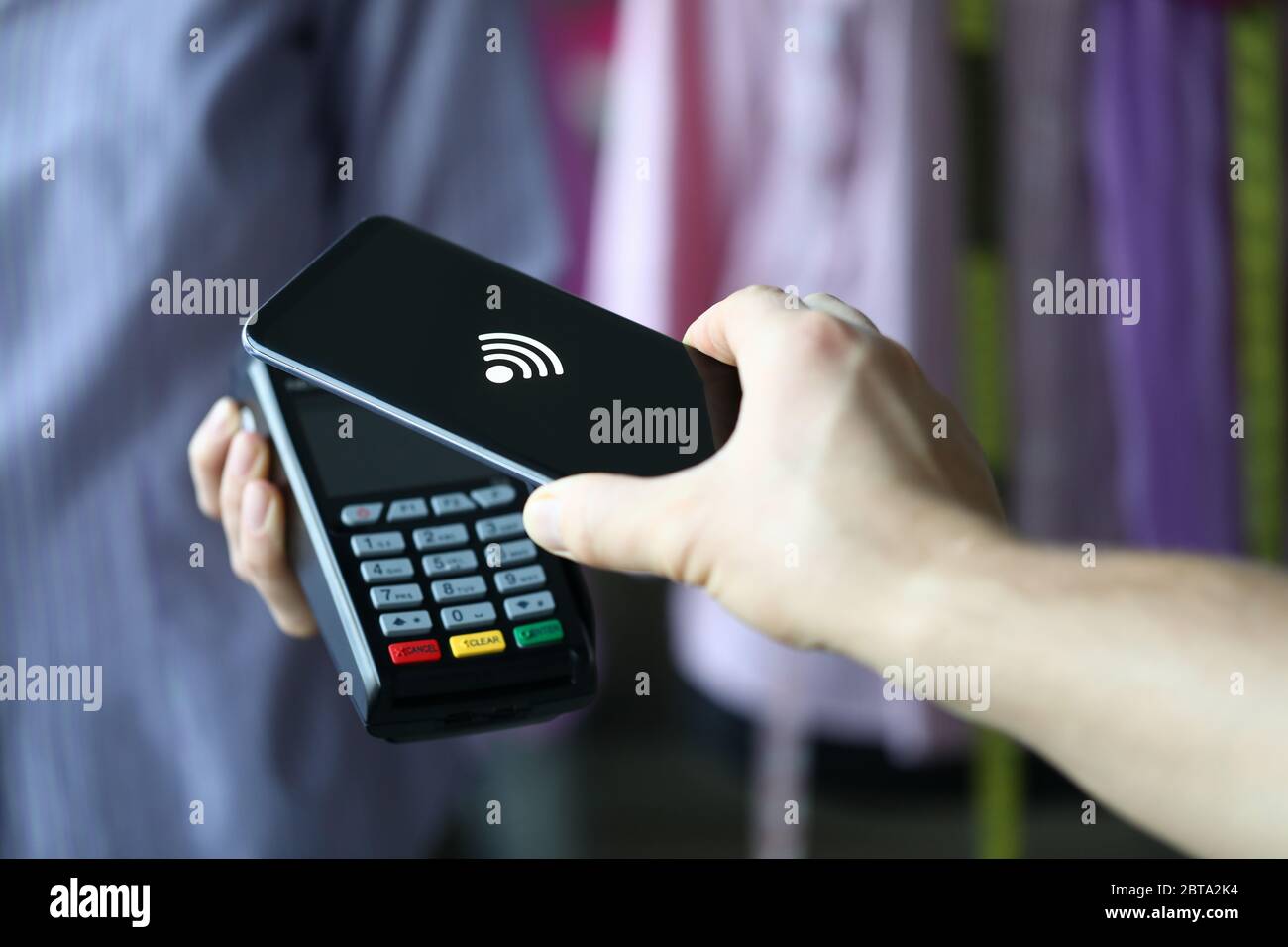 La mano tiene fuori il terminale per il pagamento con carta di credito Foto Stock