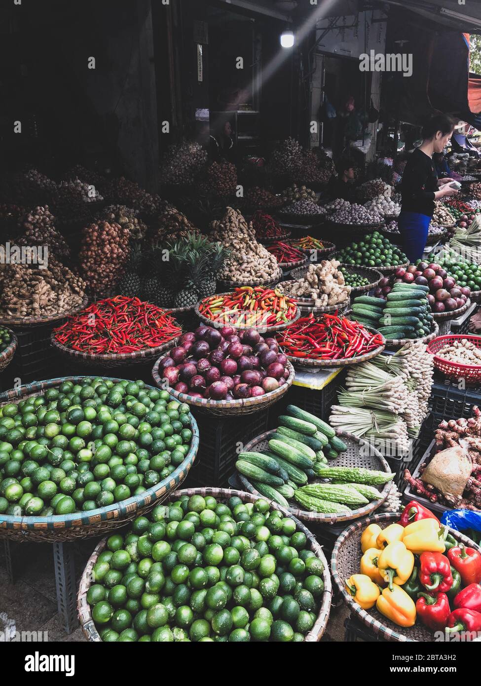Hanoi, Vietnam, 30 gennaio 2020 - Visualizza su un venditore nel mezzo di un vasto assortimento di righe di verdure sciolte e frutta in vendita in una strada. Breve Foto Stock