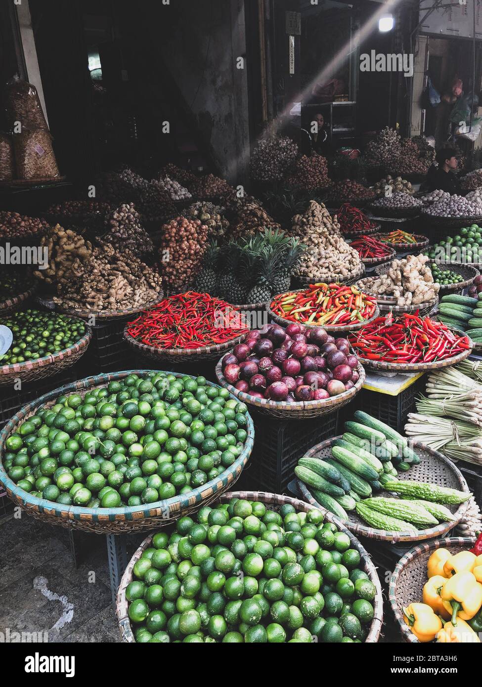 Hanoi, Vietnam, 30 gennaio 2020 - Visualizza su un venditore nel mezzo di un vasto assortimento di righe di verdure sciolte e frutta in vendita in una strada. Breve Foto Stock
