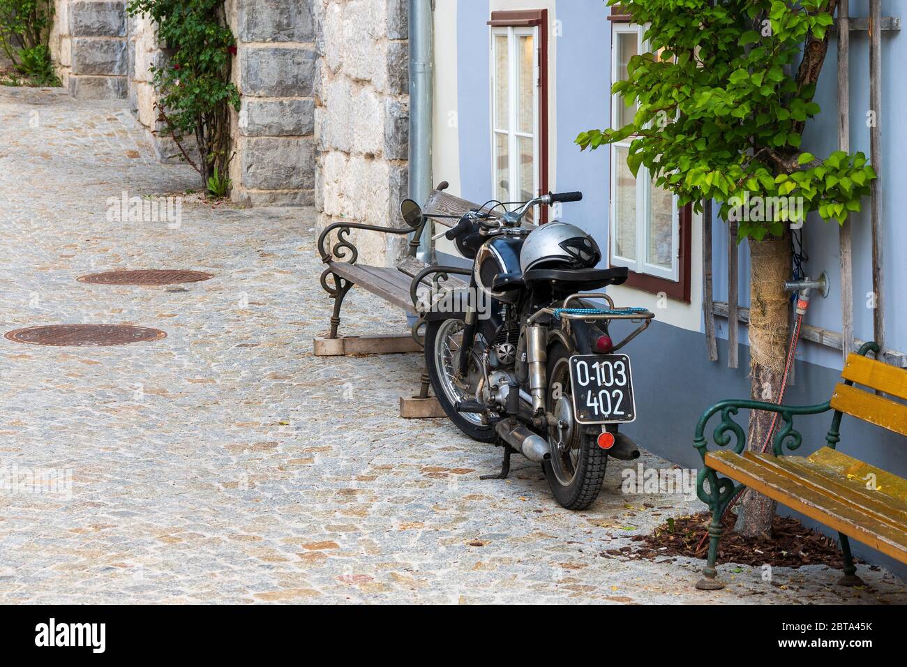 Motocicletta storica "Puch Maurersax" con vecchia targa austriaca accanto ad una casa con albero di spalliera a Hallstatt, Salzkammergut, Austria Foto Stock