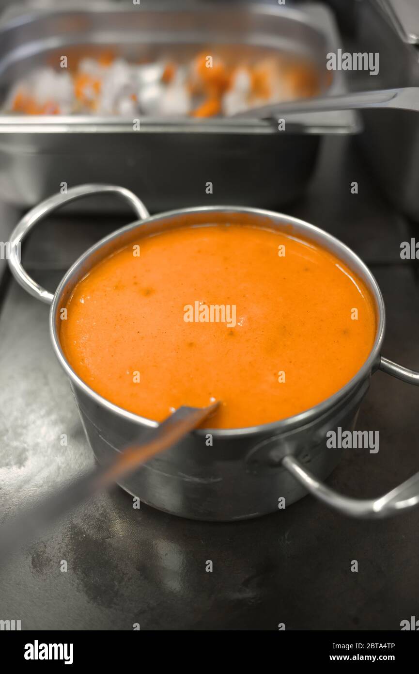 Zuppa gialla in un recipiente di metallo. Preparazione del pranzo nella sala da pranzo. Stufato esotico. Cibo in una piastra di acciaio. Foto Stock