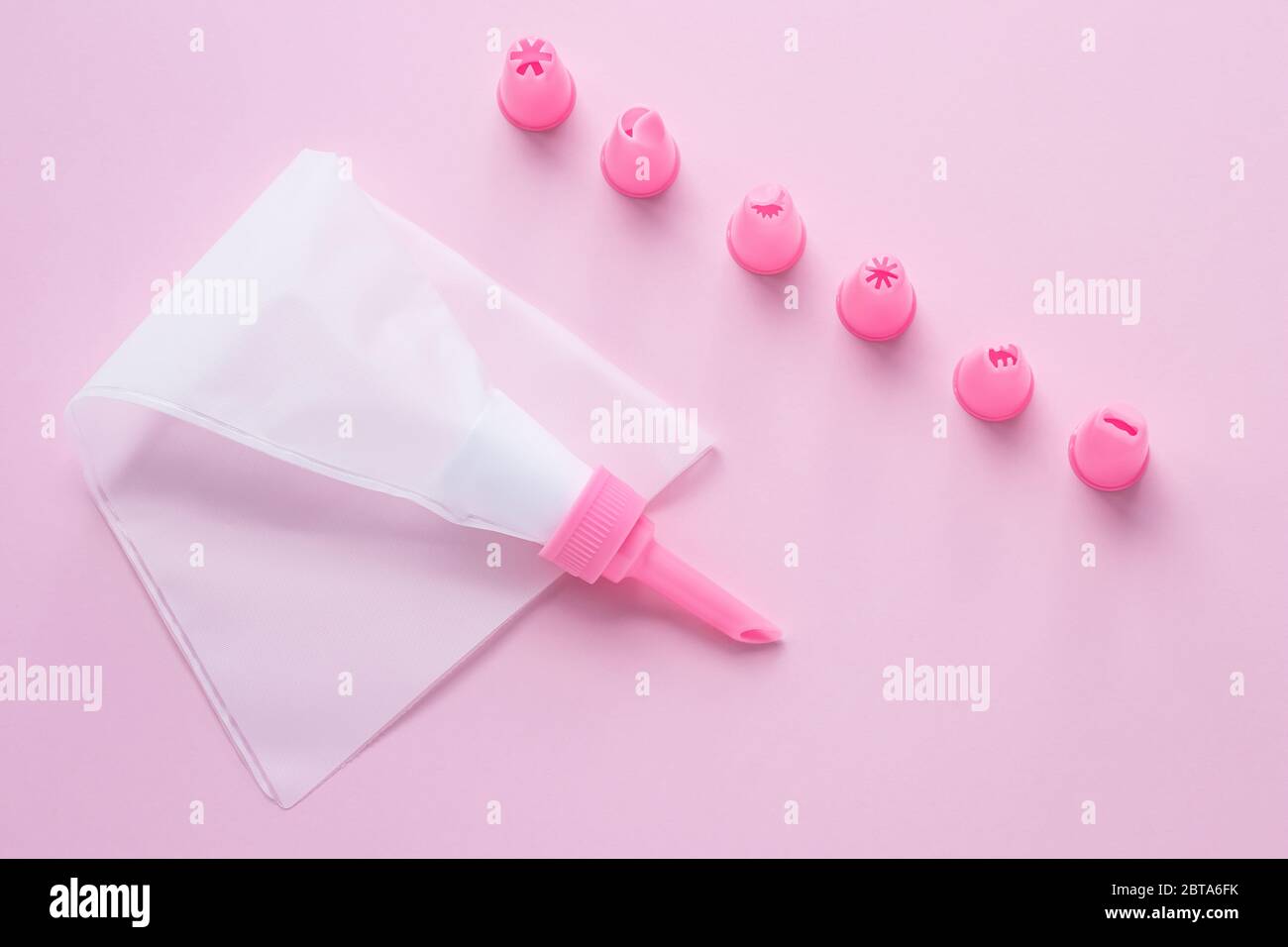 Strumenti di decorazione per torte, il sacchetto di pasticceria con ugelli  su sfondo rosa per la decorazione della torta. Concetto di cucina con crema  Foto stock - Alamy