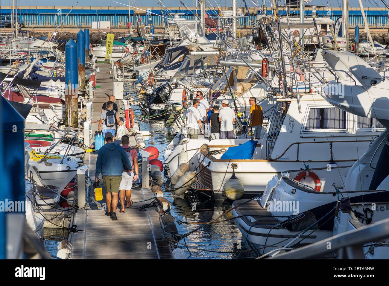 Un piccolo gruppo di persone che si imbarcherà su una barca per un viaggio in mare dal porto turistico di Puerto Colon durante la fase uno della deescalation del Covid 19, coro Foto Stock