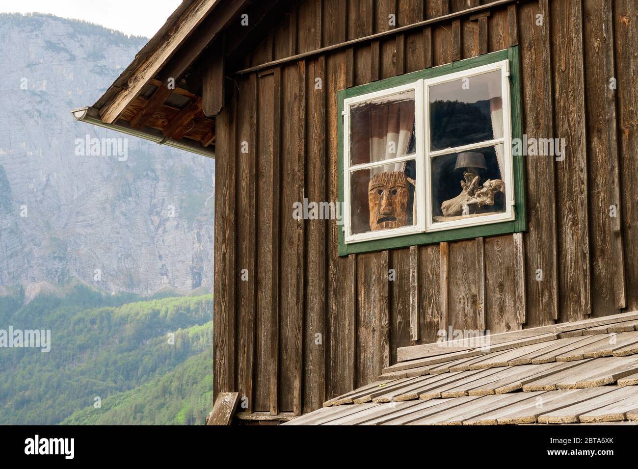 Una faccia antropomorfa scolpita di una specie di Woodwose usata come decorazione in una finestra di una vecchia casa tradizionale a Hallstatt, Salzkammergut, Austria Foto Stock