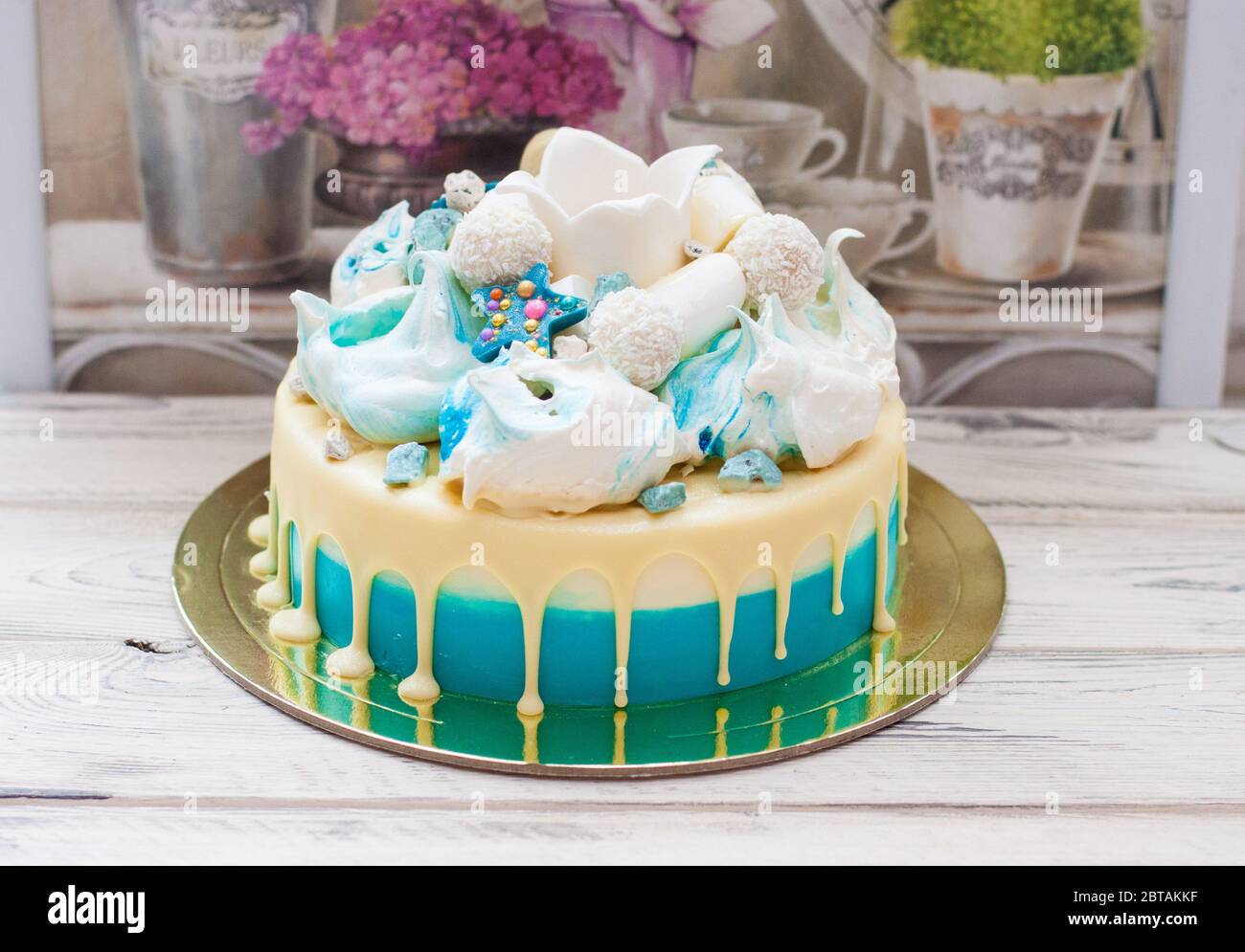 Torta blu con cioccolato bianco fuso, meringhe e corona fondente. Sfondo rustico. Foto Stock