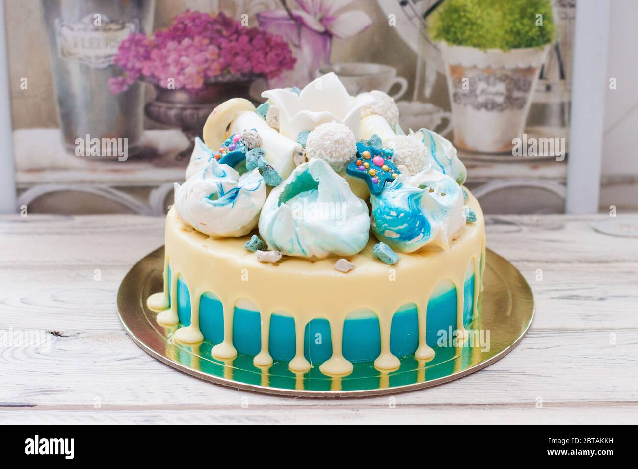 Torta blu con cioccolato bianco fuso, meringhe e corona fondente. Sfondo rustico. Foto Stock