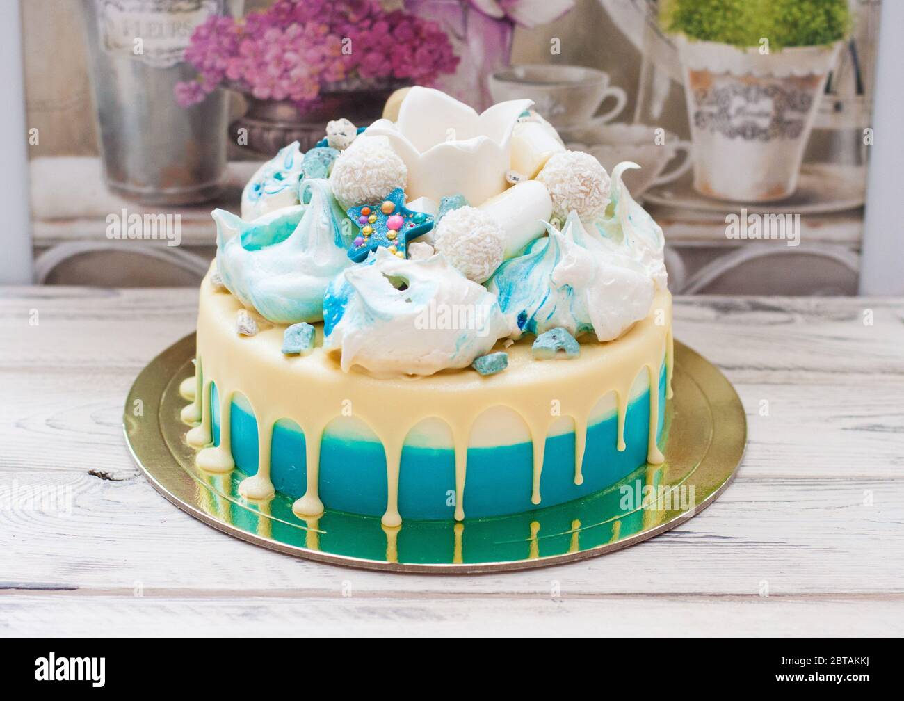 Torta blu con cioccolato bianco fuso, meringhe e corona fondente. Sfondo rustico. Foto Stock