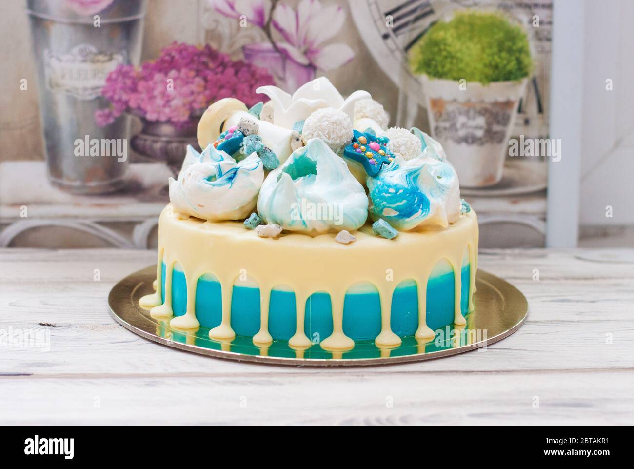 Torta blu con cioccolato bianco fuso, meringhe e corona fondente. Sfondo rustico. Foto Stock