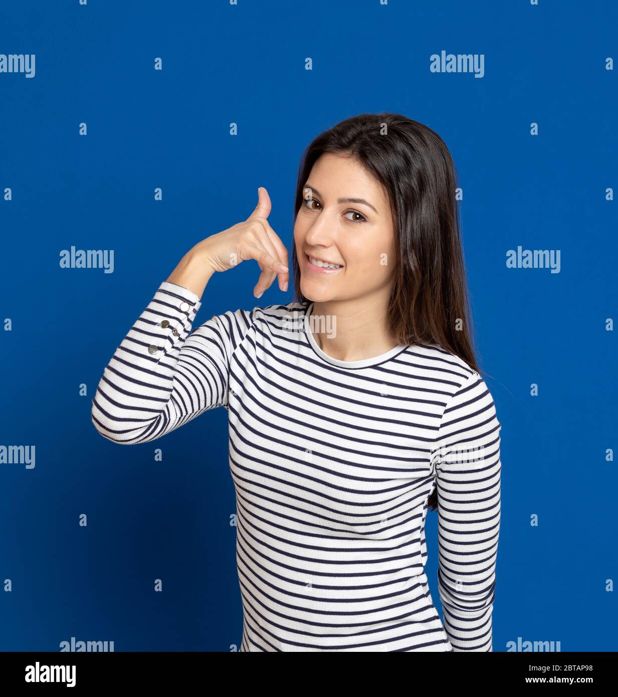 Giovane donna bruna con una T-shirt a righe su sfondo blu Foto Stock