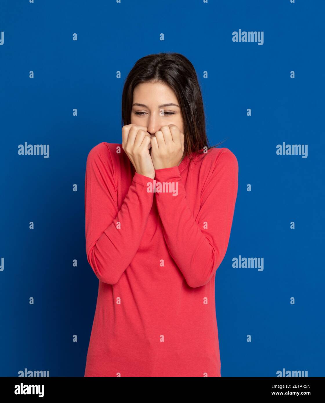 Giovane donna bruna con una T-shirt rossa su sfondo blu Foto Stock