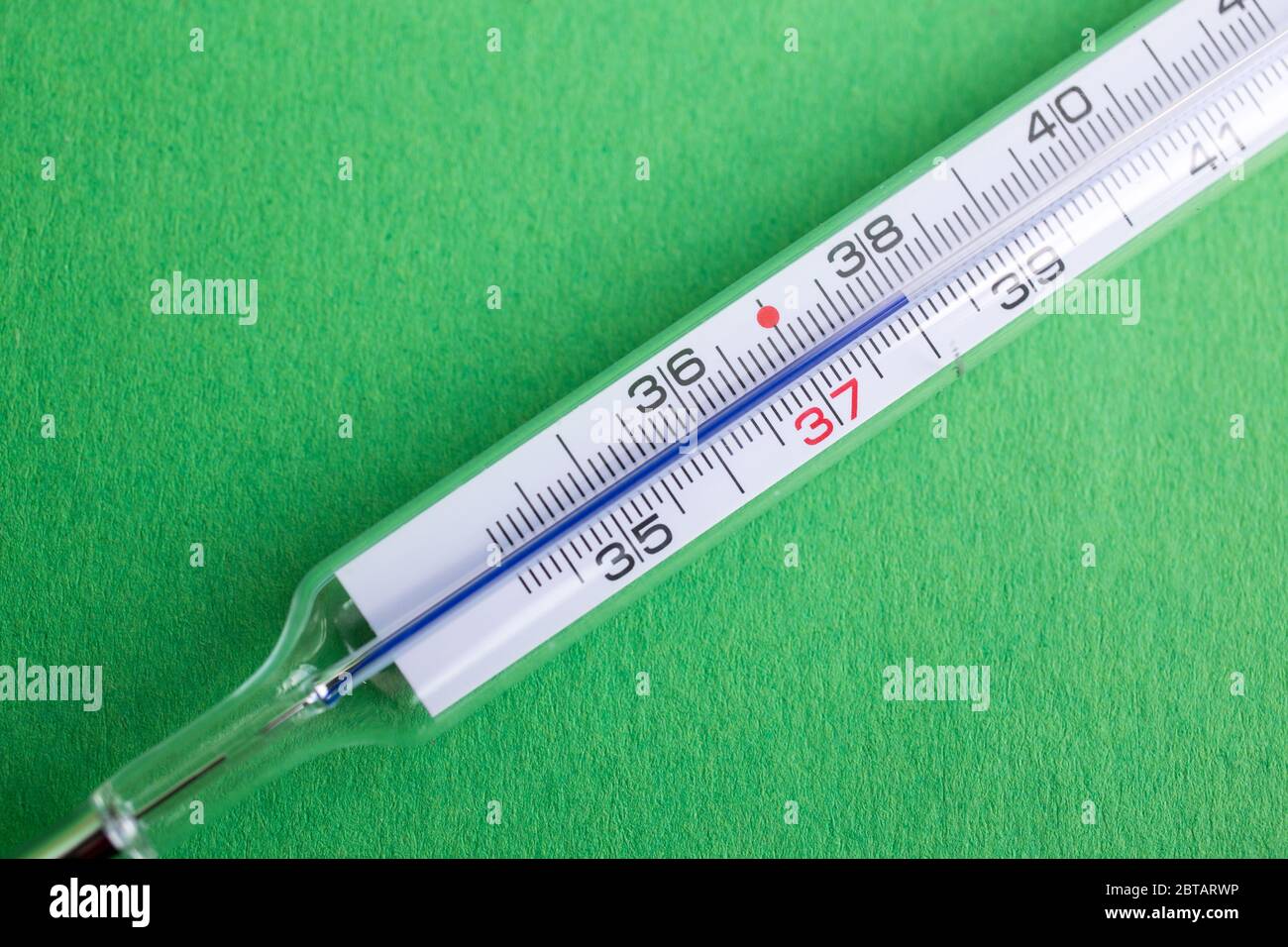 Termometro analogico a mercurio con temperatura di 37,7 °C, febbre,  influenza, virus della corona, covid19, su sfondo verde Foto stock - Alamy