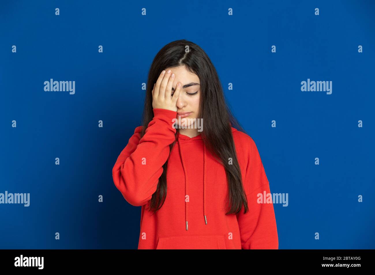 Giovane ragazza brunetta con una maglia rossa su sfondo blu Foto Stock