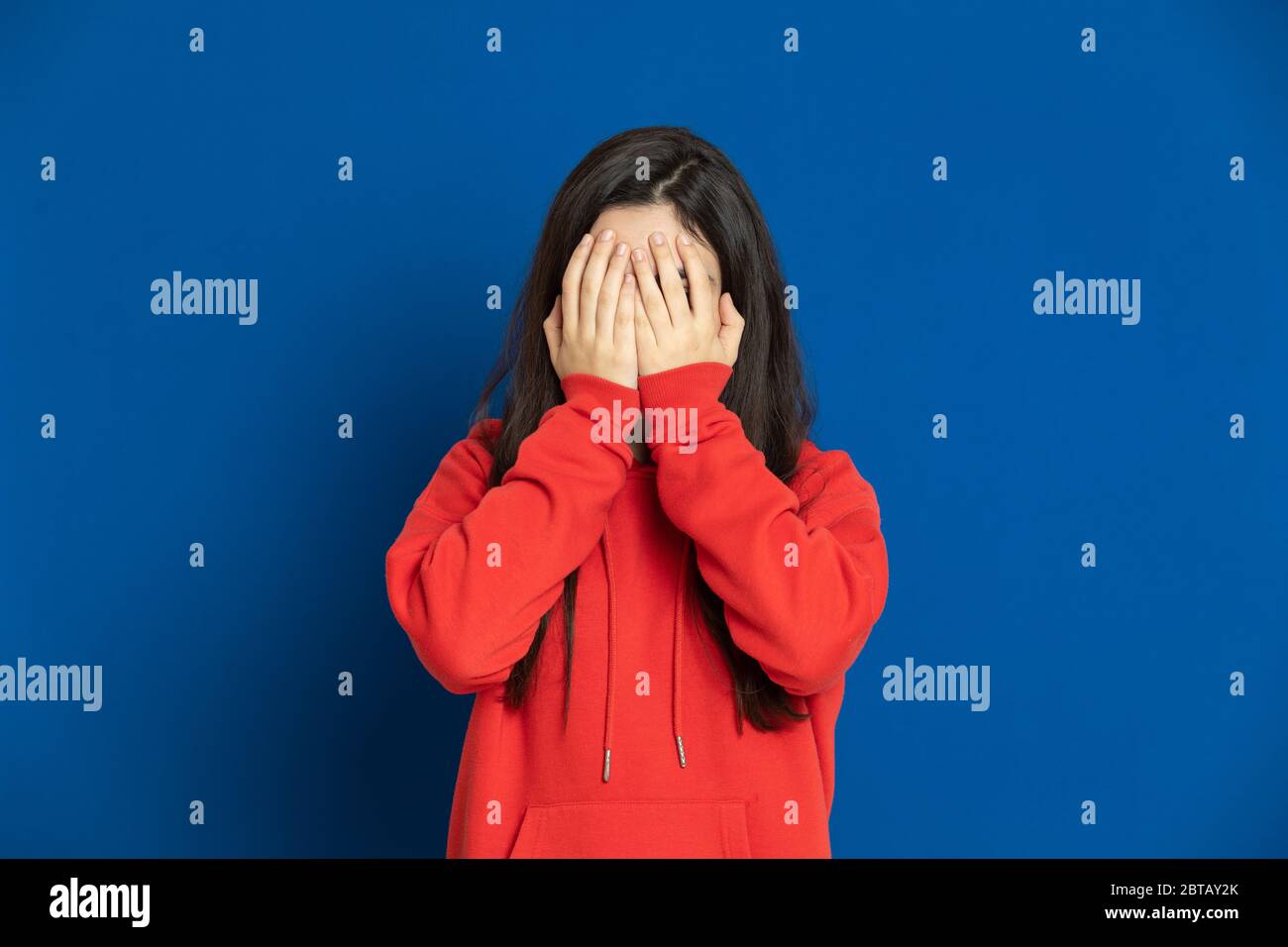 Giovane ragazza brunetta con una maglia rossa su sfondo blu Foto Stock