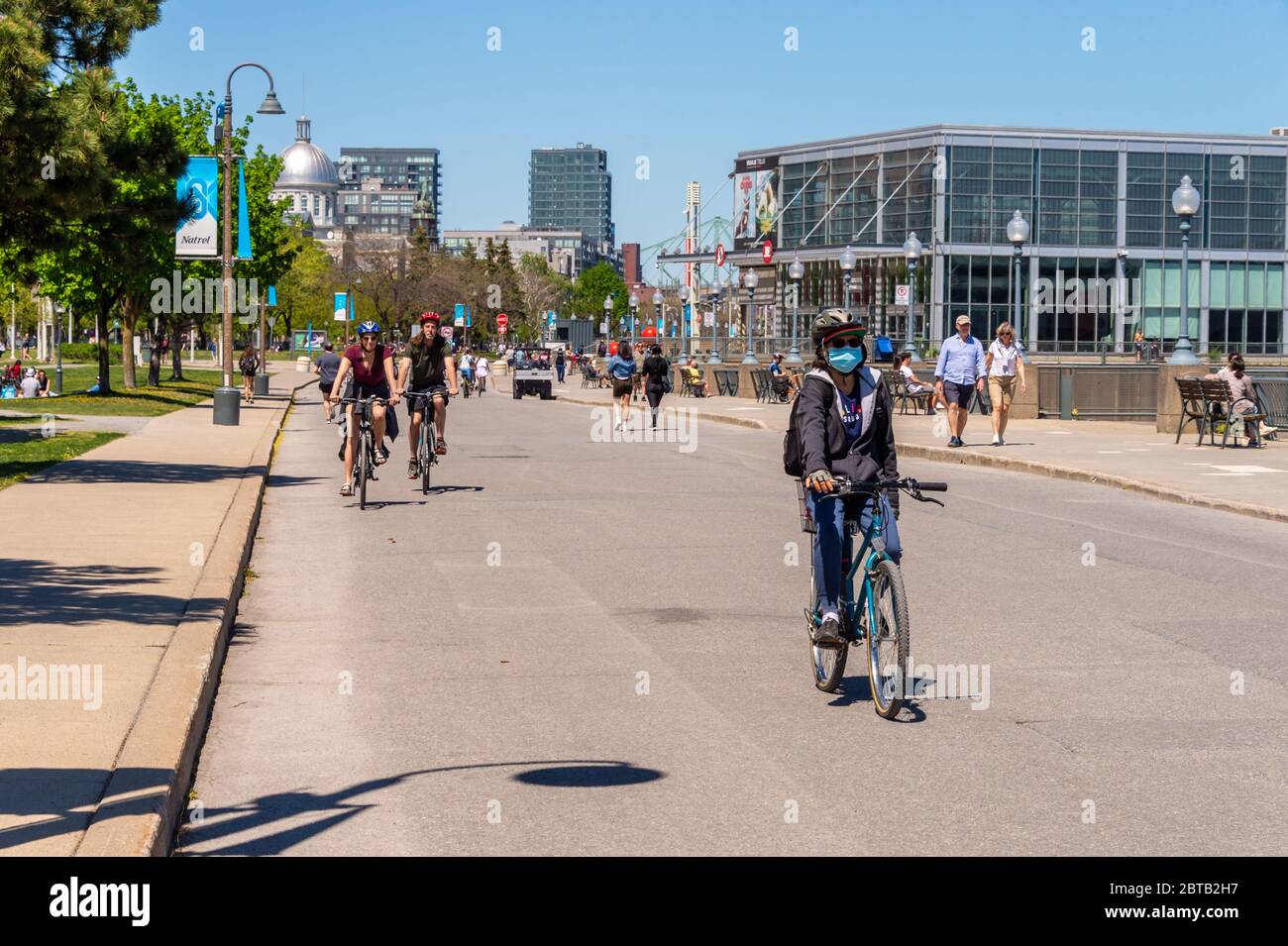Montreal, CA - 23 Maggio 2020: Donna che guida una bicicletta con maschera facciale per la protezione dal COVID-19 al Porto Vecchio. Foto Stock