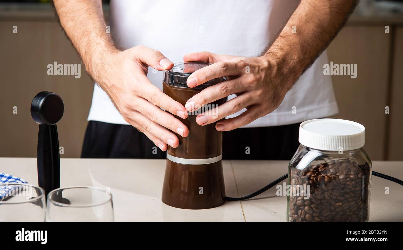 Uomo che macina i chicchi di caffè per preparare un espresso. Home barista concetto di stile di vita indoor Foto Stock