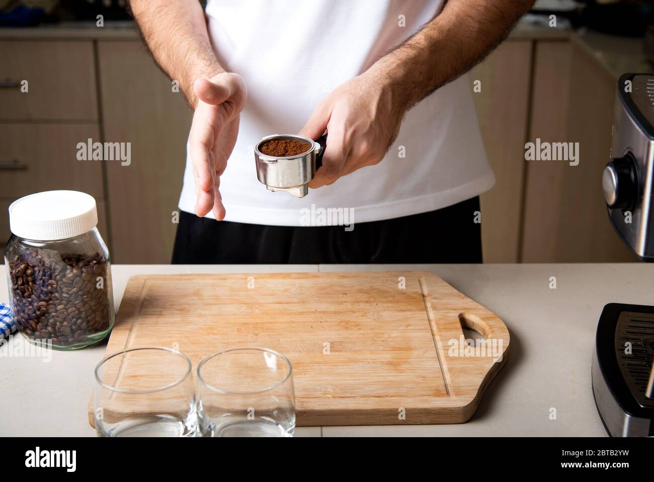 Uomo che dispone la polvere macinata di caffè nel cestino portafiltro. Home barista concetto di stile di vita indoor Foto Stock
