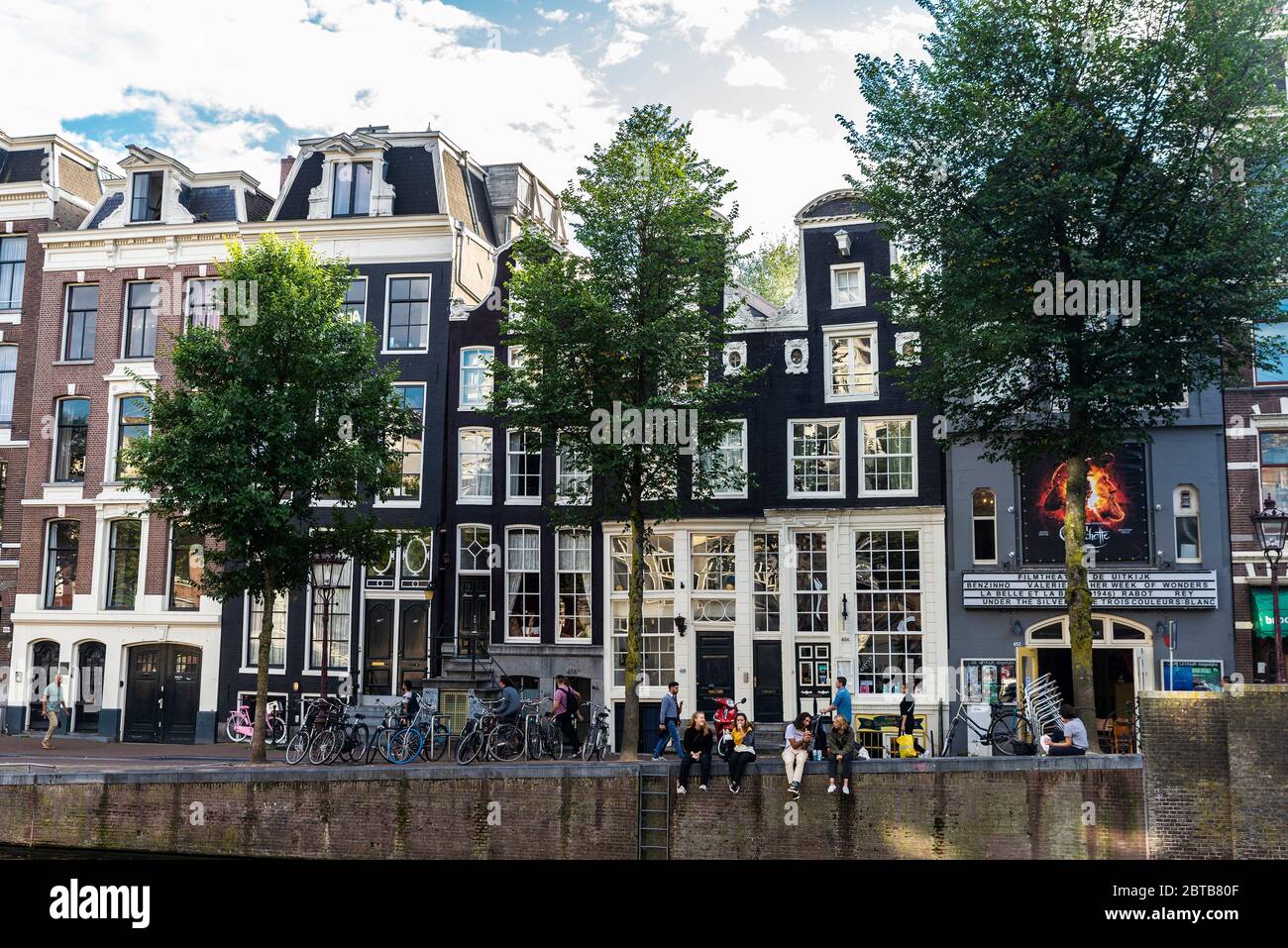 Amsterdam, Paesi Bassi - 9 settembre 2018: Vecchie case tradizionali pendenti lungo un canale con gente intorno nella città vecchia di Amsterdam, Paesi Bassi Foto Stock