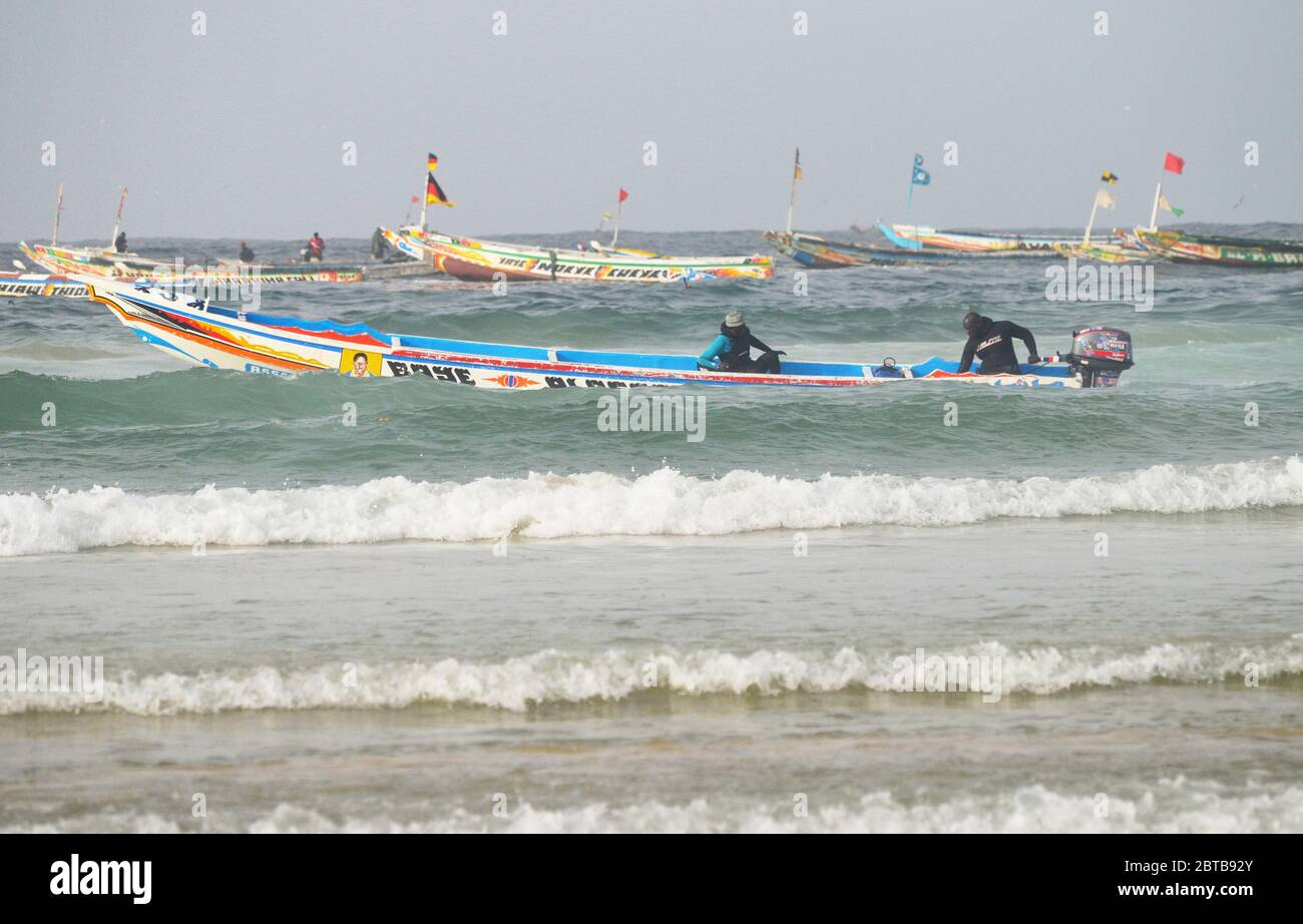 Una piroga (barca artigianale da pesca) che bravura il surf a Yoff Beach, Dakar, Senegal Foto Stock