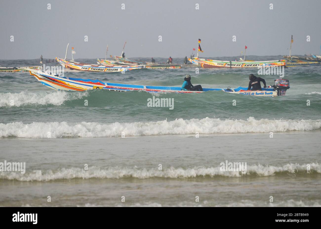 Una piroga (barca artigianale da pesca) che bravura il surf a Yoff Beach, Dakar, Senegal Foto Stock