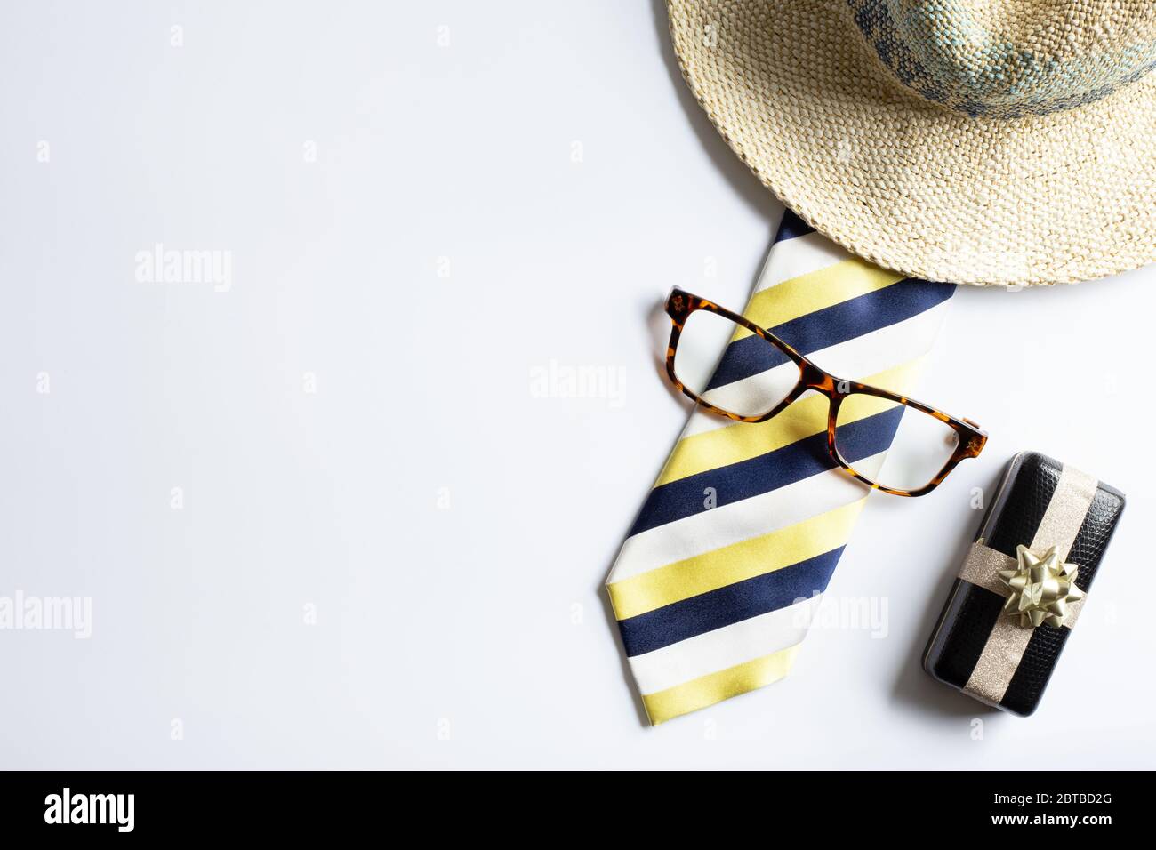 Cravatta stripy gialla da uomo, confezione regalo confezionata, occhiali, cappello straywsummer su sfondo bianco. Disposizione piatta, vista dall'alto. Concetto di giorno del padre felice Foto Stock