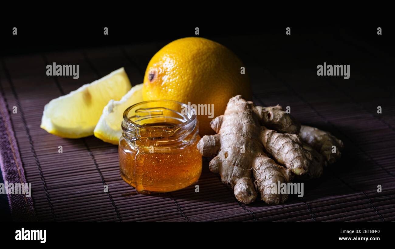 ancora vita zenzero, limone e un vaso di miele su uno sfondo scuro Foto Stock