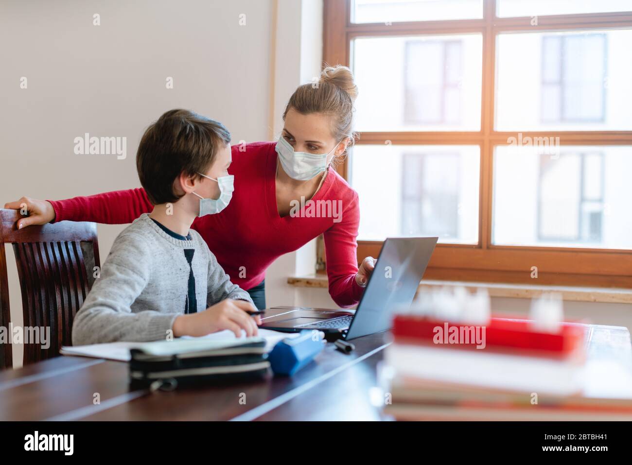 Madre e bambino che hanno una sessione di e-learning con l'insegnante durante la crisi Foto Stock