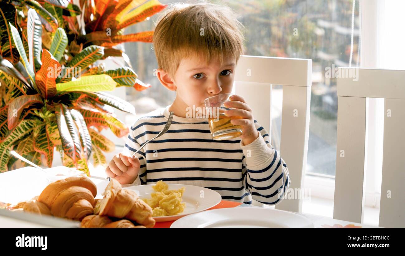 Ritratto del bambino carino che ha fatto colazione e beve succo di mela Foto Stock